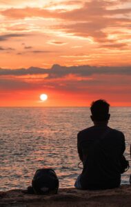 Person silhouetted against a sunset over the ocean representing personal growth and reflection