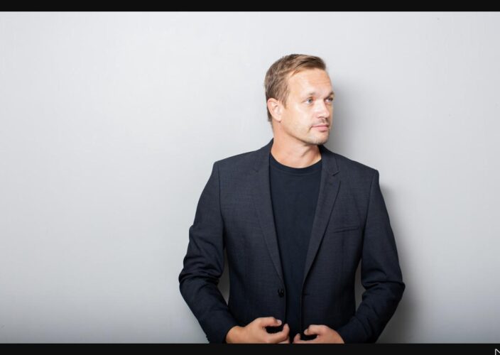 A thoughtful business leader in a dark suit looking to the side, reflecting on a major decision