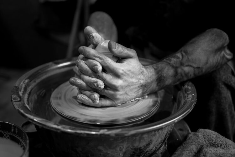 Hands shaping clay on a pottery wheel representing identity as a conversation